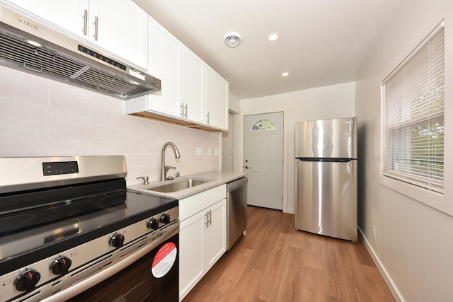 4212 N 53rd St, Milwaukee, WI 53216 - kitchen featuring appliances with stainless steel finishes, under cabinet range hood, a sink, decorative backsplash, and light wood-style floors
