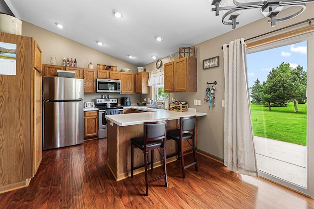 W7009 Crestwood Ln, Fond Du Lac, WI 54937 - kitchen with appliances with stainless steel finishes, brown cabinetry, a peninsula, light countertops, and dark wood-style floors