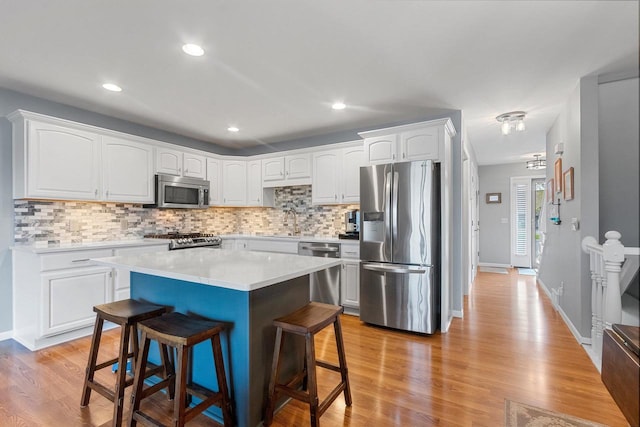 1243 Pond View Cir, De Pere, WI 54115 - kitchen with appliances with stainless steel finishes, a breakfast bar area, backsplash, white cabinets, and recessed lighting