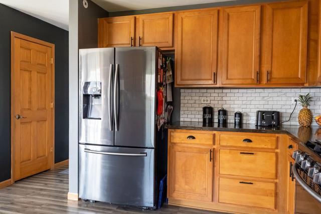 516 Prairie Point Dr, Poplar Grove, IL 61065 - kitchen with stainless steel appliances, wood finished floors, brown cabinetry, tasteful backsplash, and baseboards
