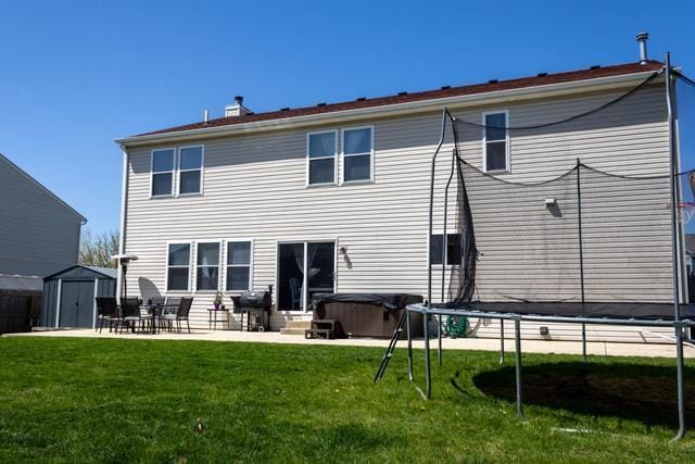 516 Prairie Point Dr, Poplar Grove, IL 61065 - rear view of house featuring a hot tub, a patio area, a trampoline, and a lawn