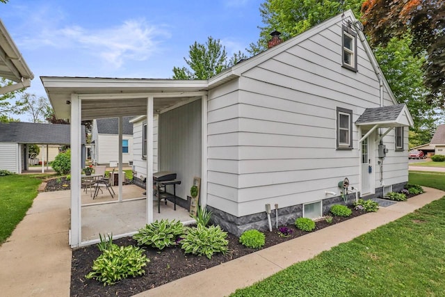 340 12th St S, Wisconsin Rapids, WI 54494 - view of side of home with a chimney, a patio area, and a yard