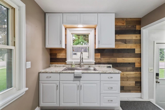 340 12th St S, Wisconsin Rapids, WI 54494 - kitchen with a sink, wood walls, white cabinetry, plenty of natural light, and light stone counters