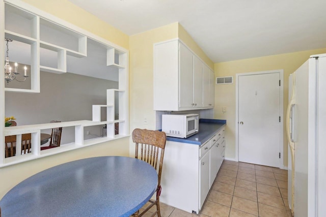 219 Summit St, Portage, WI 53901 - kitchen with white appliances, white cabinets, light tile patterned flooring, a chandelier, and dark countertops