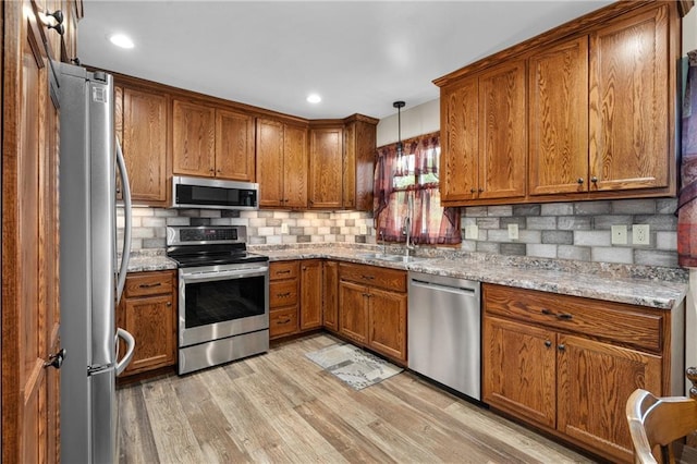 12924 Thomas St, Osseo, WI 54758 - kitchen featuring appliances with stainless steel finishes, a sink, brown cabinets, backsplash, and recessed lighting