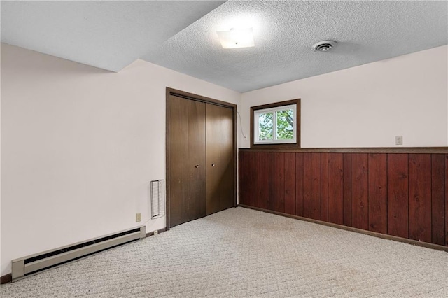 12924 Thomas St, Osseo, WI 54758 - unfurnished bedroom with a closet, carpet floors, baseboard heating, wainscoting, and wood walls