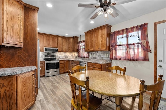 12924 Thomas St, Osseo, WI 54758 - kitchen with appliances with stainless steel finishes, brown cabinetry, decorative backsplash, light wood-style flooring, and ceiling fan