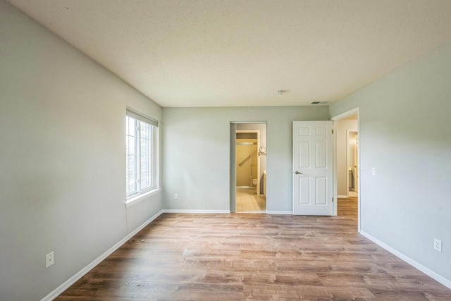 1402 Wheeler Rd Unit A, Madison, WI 53704 - unfurnished bedroom featuring wood finished floors, a textured ceiling, baseboards, and ensuite bathroom