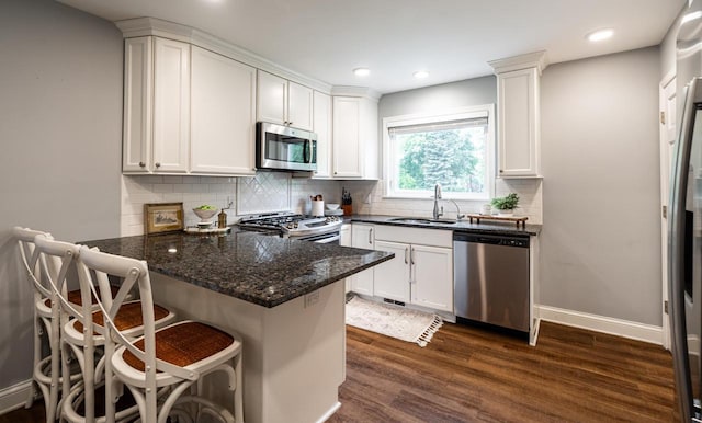 640 Crystal Ln, Elm Grove, WI 53122 - kitchen with appliances with stainless steel finishes, a sink, dark wood-style floors, a peninsula, and white cabinets
