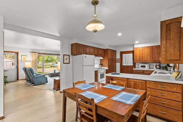 404 W Albert St, Portage, WI 53901 - kitchen with white appliances, light countertops, light wood-style flooring, brown cabinets, and hanging light fixtures