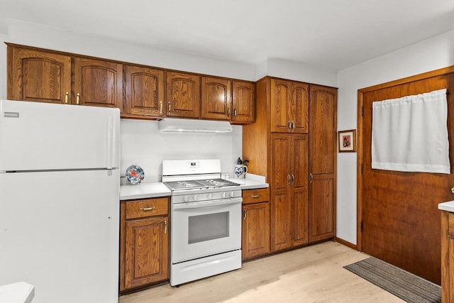 404 W Albert St, Portage, WI 53901 - kitchen featuring white appliances, under cabinet range hood, light wood-type flooring, light countertops, and brown cabinets