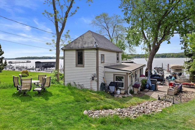 N26W30255 Maple Ave, Pewaukee, WI 53072 - rear view of house featuring a water view, a lawn, a patio area, and a shingled roof