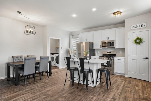 972 Margarets Way, Belleville, WI 53508 - kitchen featuring appliances with stainless steel finishes, washer and clothes dryer, a breakfast bar area, dark wood-style flooring, and recessed lighting