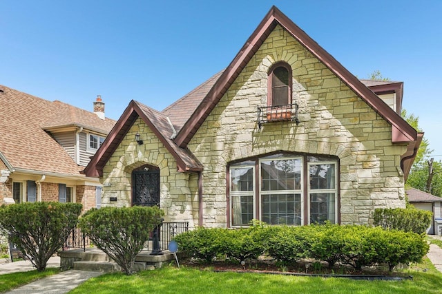 4182 N 13th St, Milwaukee, WI 53209 - tudor home featuring stone siding, a shingled roof, and a chimney