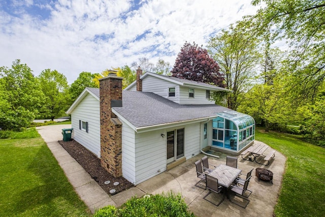 12105 W Shawnee Pass, Mequon, WI 53097 - back of property with a patio area, roof with shingles, a sunroom, a chimney, and an outdoor fire pit