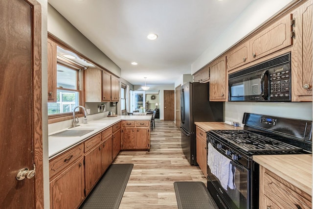 12105 W Shawnee Pass, Mequon, WI 53097 - kitchen featuring black appliances, light countertops, a sink, light wood-type flooring, and a peninsula