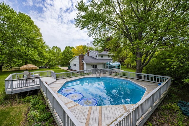 12105 W Shawnee Pass, Mequon, WI 53097 - outdoor pool with a deck, view of wooded area, and a lawn