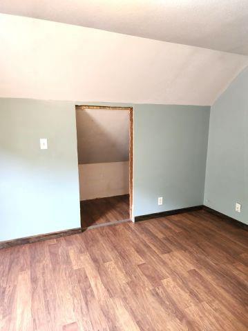 1561 240th Ave, Luck, WI 54853 - unfurnished room with vaulted ceiling, baseboards, and wood finished floors