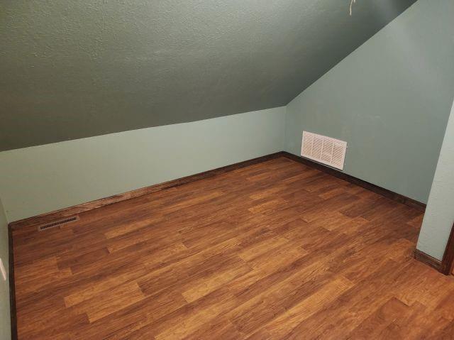1561 240th Ave, Luck, WI 54853 - additional living space with vaulted ceiling, dark wood-style flooring, baseboards, and a textured ceiling