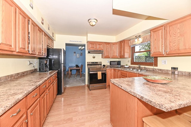 7538 S 74th St, Franklin, WI 53132 - kitchen featuring appliances with stainless steel finishes, a sink, light wood finished floors, under cabinet range hood, and a kitchen breakfast bar
