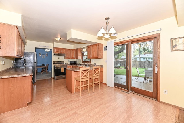 7538 S 74th St, Franklin, WI 53132 - kitchen featuring stainless steel appliances, under cabinet range hood, a chandelier, light wood-style flooring, and a kitchen bar