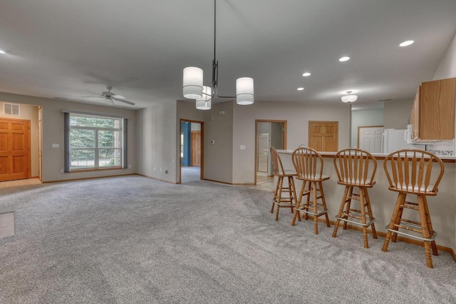 W159N4872 Graysland Dr, Menomonee Falls, WI 53051 - kitchen featuring a ceiling fan, light colored carpet, a kitchen bar, baseboards, and a peninsula