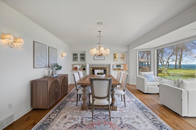4696 N Lake Dr, Whitefish Bay, WI 53211 - dining space featuring a chandelier, wood finished floors, built in features, ornamental molding, and a water view
