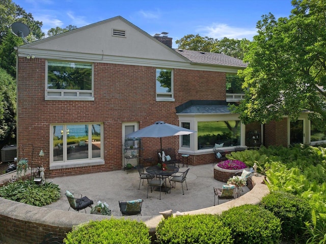 4696 N Lake Dr, Whitefish Bay, WI 53211 - back of house featuring a patio area, a chimney, and brick siding