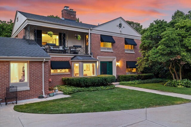 4696 N Lake Dr, Whitefish Bay, WI 53211 - view of front of property with a chimney, brick siding, a yard, a balcony, and roof with shingles