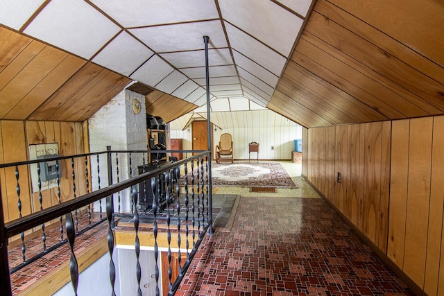 917 Whitewater Ave, Fort Atkinson, WI 53538 - hall with wooden walls, vaulted ceiling, an upstairs landing, and brick patterned floors