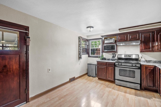 2049 S 77th St, West Allis, WI 53219 - kitchen featuring appliances with stainless steel finishes, under cabinet range hood, a textured wall, light wood finished floors, and baseboards