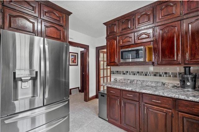 2049 S 77th St, West Allis, WI 53219 - kitchen with appliances with stainless steel finishes, decorative backsplash, light tile patterned flooring, a textured ceiling, and light stone countertops