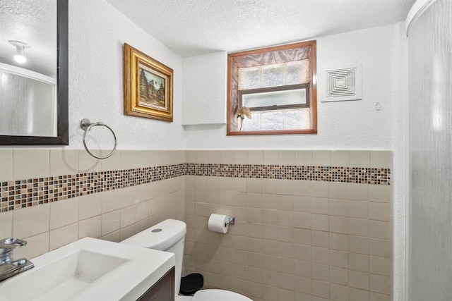 2049 S 77th St, West Allis, WI 53219 - bathroom featuring tile walls, a textured ceiling, toilet, vanity, and a textured wall