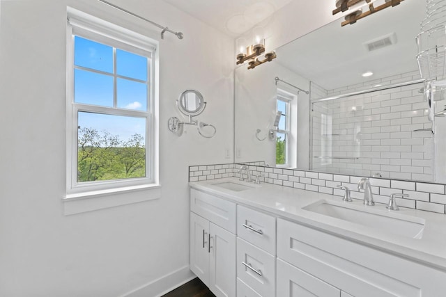 529 Century Oak Dr, Waukesha, WI 53188 - bathroom featuring plenty of natural light, double vanity, a tile shower, and tasteful backsplash