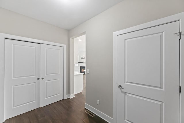 529 Century Oak Dr, Waukesha, WI 53188 - unfurnished bedroom with dark wood-type flooring, a closet, baseboards, and a glass covered fireplace