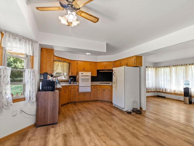 9446 W Lynx Ct, Milwaukee, WI 53225 - kitchen with white appliances, a warming drawer, light wood-type flooring, brown cabinetry, and healthy amount of natural light