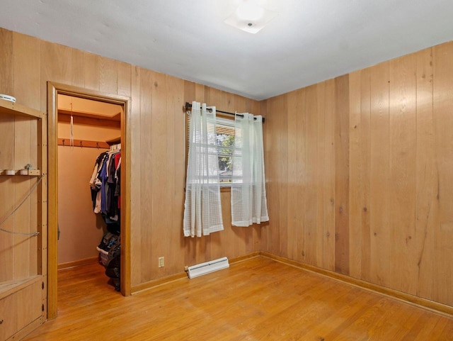 9446 W Lynx Ct, Milwaukee, WI 53225 - unfurnished bedroom with a spacious closet, wood finished floors, a closet, a baseboard radiator, and wood walls