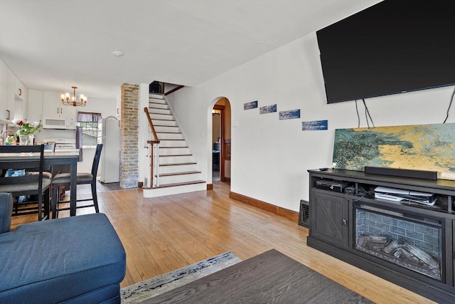 901 William St, Racine, WI 53402 - living area with stairs, arched walkways, light wood finished floors, a chandelier, and baseboards