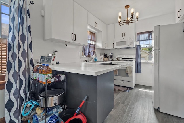 901 William St, Racine, WI 53402 - kitchen featuring white appliances, a sink, a peninsula, wood finished floors, and a chandelier