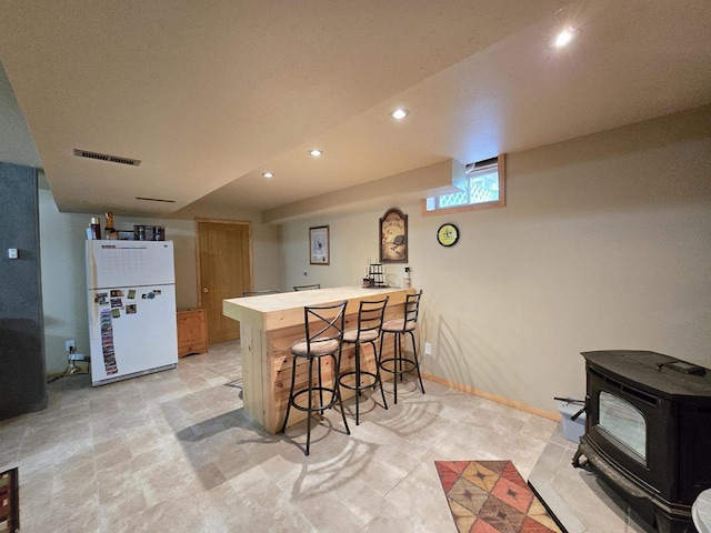 5321 Breezy Pine Dr, Wisconsin Rapids, WI 54494 - kitchen featuring freestanding refrigerator, a wood stove, recessed lighting, a peninsula, and a kitchen bar