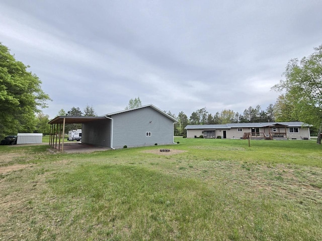 5321 Breezy Pine Dr, Wisconsin Rapids, WI 54494 - view of grassy yard with an outdoor fire pit, a carport, and an outbuilding