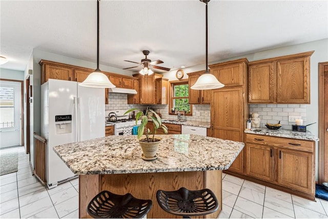 2322 243rd Ave, Cushing, WI 54006 - kitchen featuring light marble finish flooring, white appliances, under cabinet range hood, brown cabinets, and ceiling fan