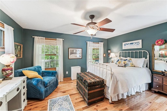 2322 243rd Ave, Cushing, WI 54006 - bedroom with multiple windows, light wood-style flooring, a textured ceiling, and a ceiling fan
