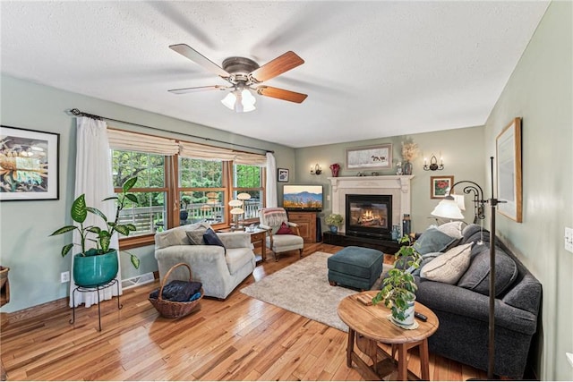 2322 243rd Ave, Cushing, WI 54006 - living room with wood finished floors, ceiling fan, a textured ceiling, a glass covered fireplace, and baseboards