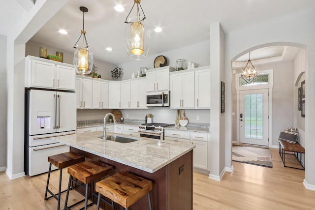 1766 Derby Ln, Oconomowoc, WI 53066 - kitchen featuring premium appliances, a sink, arched walkways, white cabinetry, and recessed lighting