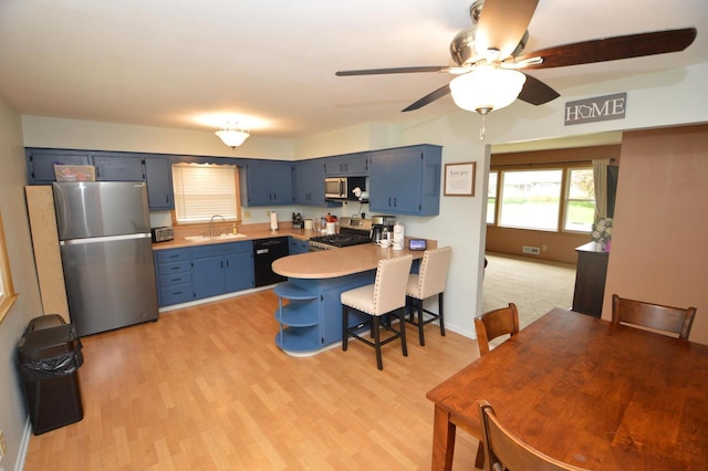 1781 Spruce Ct, South Milwaukee, WI 53172 - kitchen with stainless steel appliances, a sink, blue cabinets, a peninsula, and light wood-style flooring