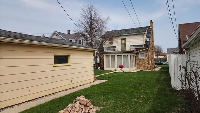 2126 S 16th St, Sheboygan, WI 53081 - rear view of property with a lawn, a balcony, a chimney, and brick siding