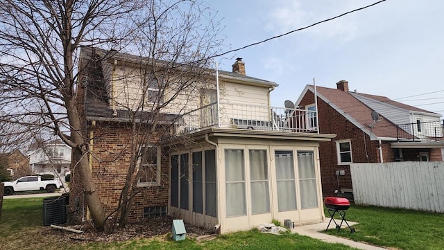2126 S 16th St, Sheboygan, WI 53081 - rear view of property featuring a balcony, a sunroom, brick siding, a chimney, and central AC unit