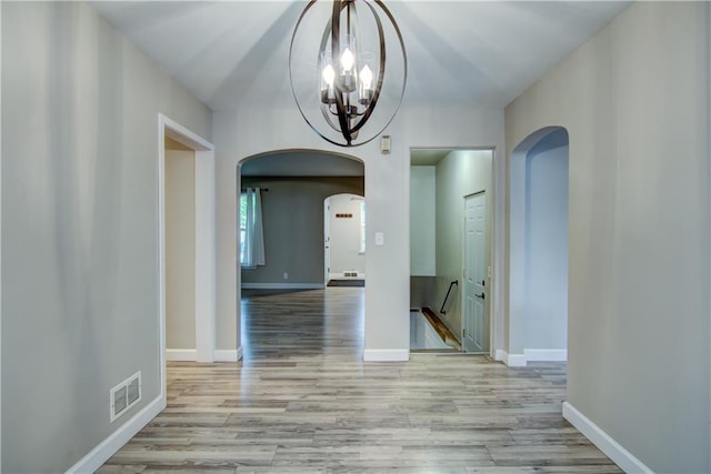 1708 Rist Ave, Eau Claire, WI 54701 - hall featuring arched walkways, a chandelier, wood finished floors, and baseboards