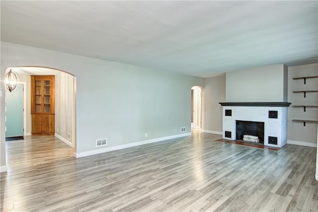 1708 Rist Ave, Eau Claire, WI 54701 - unfurnished living room featuring light wood finished floors, baseboards, arched walkways, and a brick fireplace